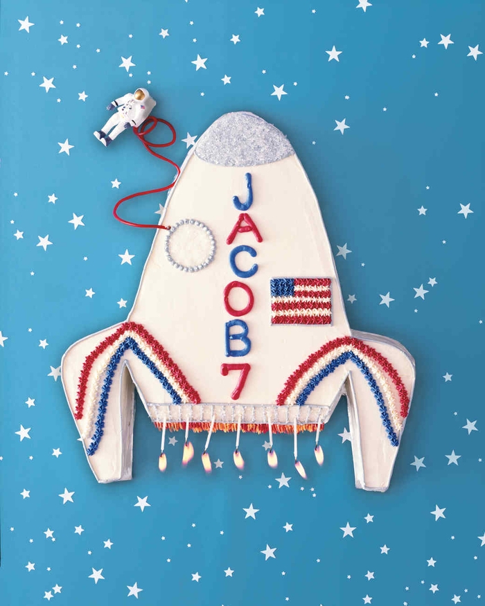 gateau d'anniversaire garçon en original en forme spatial au glaçage blanc, bleu et rouge décoré d'une petite figurine de cosmonaute
