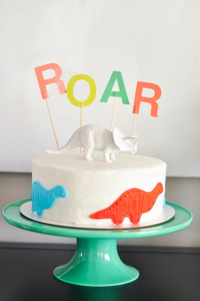 joli design de gâteau d anniversaire garçon au glaçage blanc décoré sur les côtés de petits dinosaures 