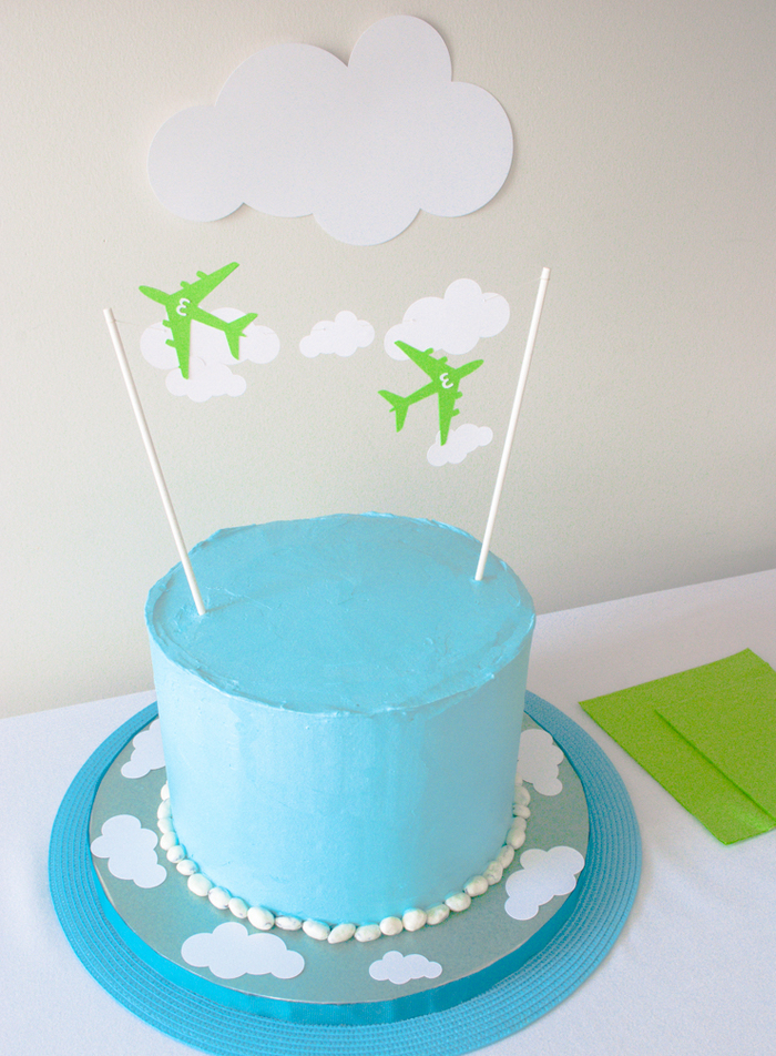 anniversaire sur thème avions avec un gateau d'anniversaire garçon au glaçage bleu décoré avec des cake-toppers avions et nuages en papier