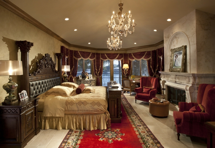 chambre style gypsy, lit beige, plafonnies somptueux, cheminée, fauteuils oranges, tête de lit en cuir