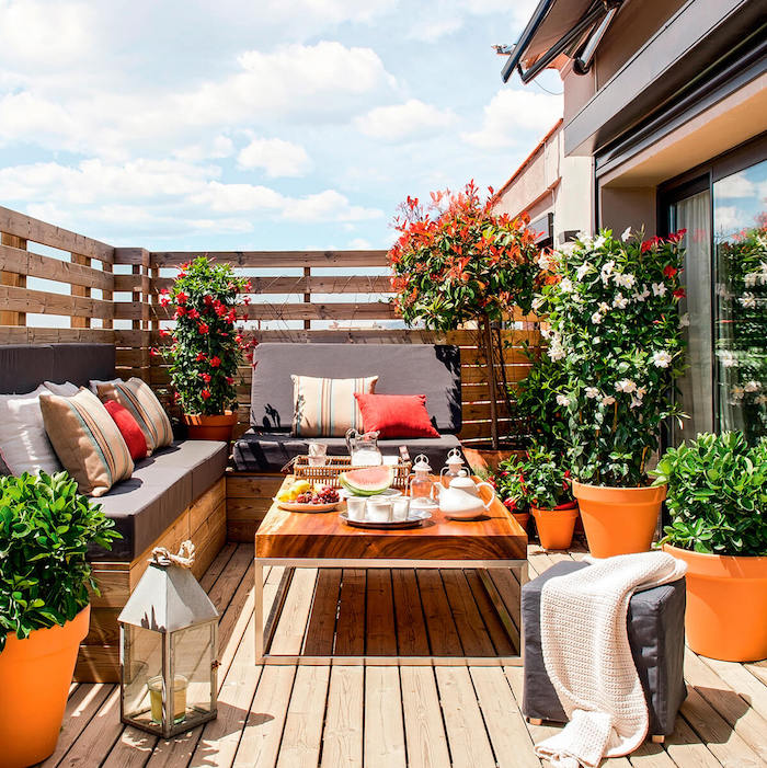 photo de terrasse fleurie avec pots de fleurs et jardinieres oranges, barriere en bois pour balcon contre vis a vis