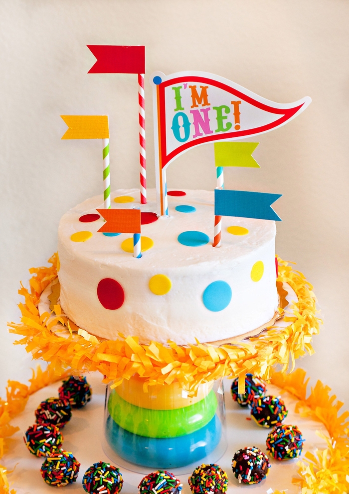 idée pour un gateau anniversaire 1 an facile à décorer soi-même, au glaçage blanc décoré de ronds en pâte à sucre coloré, pailles et fanions