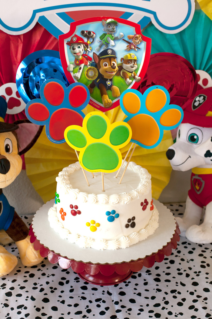 gâteau d'anniversaire garçon sur le thème la pat patrouille au glaçage blanc décoré de cake toppers pattes en papier