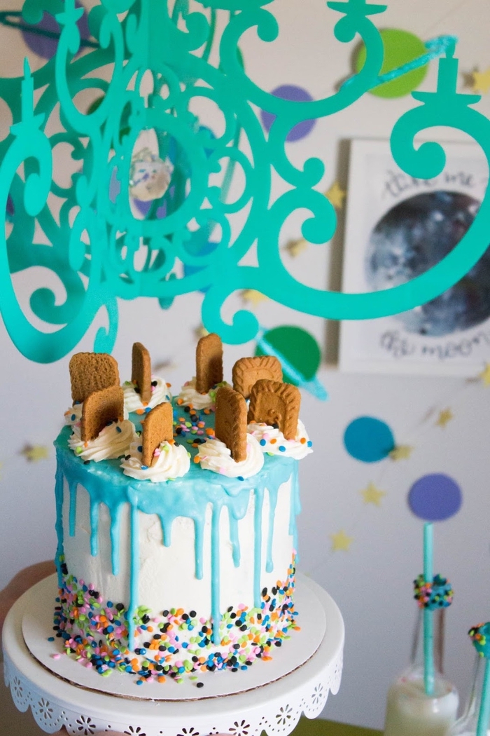 gateau d'anniversaire personnalisé au glaçage bleu pastel coulant décoré de biscuits et de confettis colorés