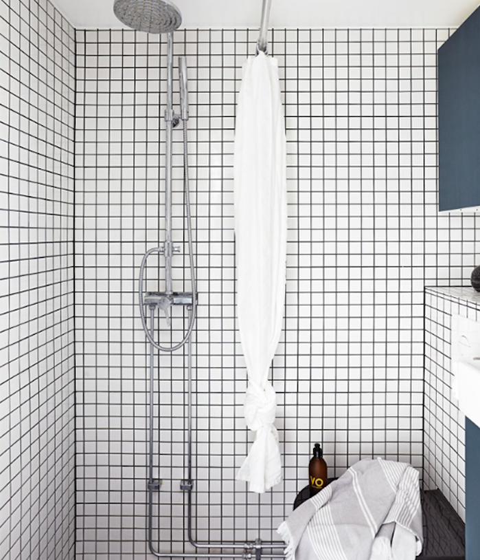 modele de petite salle de bain design avec carrelage mural blanc, douche argent, et meubles de rangement bleus