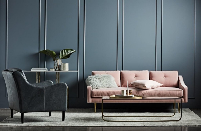 déco de salon foncé avec table à design métallique combinée avec canapé rose poudré et fauteuil de cuir noir sur tapis gris clair