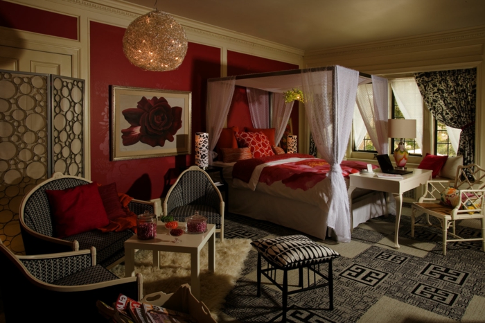 mur et couettes couleur bordeau, chaises et table basse élégante, lit avec rideaux