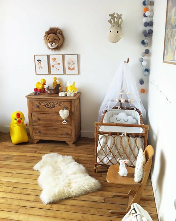 cadre chambre bébé, décoration chambre bébé fille, meuble vintage en bois marron, parquet en bois clair, chaise en bois, guirlande de pompons colorés dans un angle 