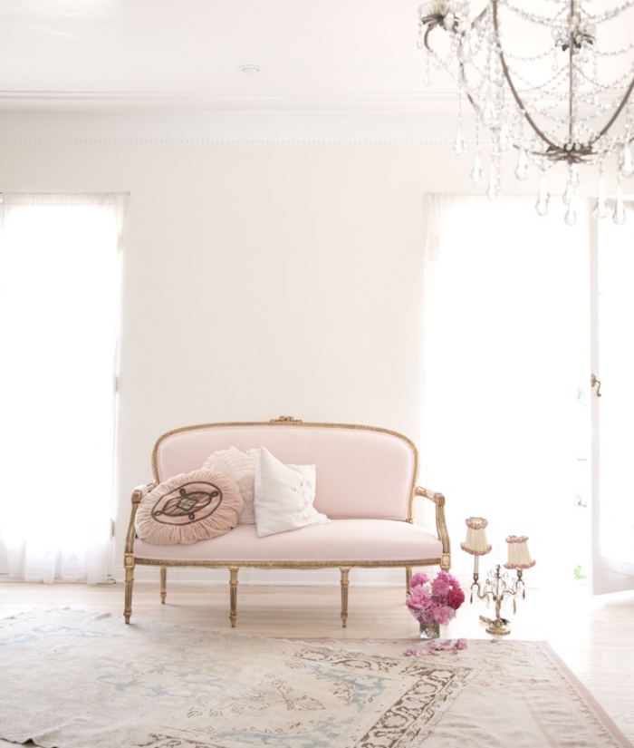 idée déco rétro chic dans un salon aux murs blancs avec parquet clair aménagé avec canapé en rose pastel et or
