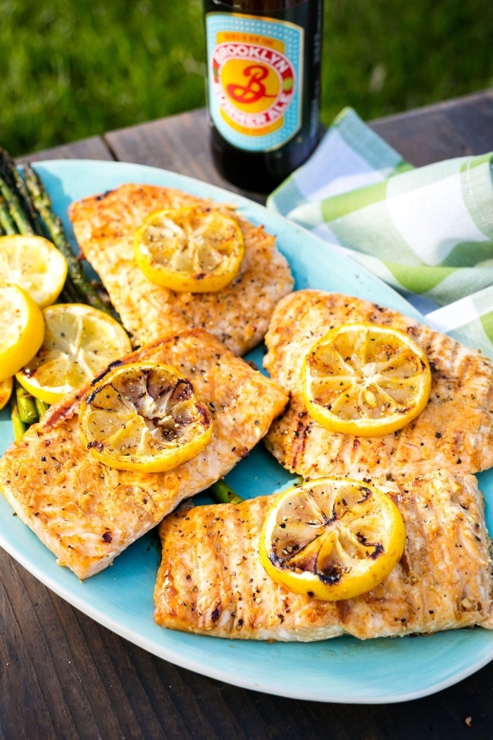 repas du soir léger, recette de tranches de saumon grillé avec garniture de citron et aubergines rôti servis dans une assiette bleue