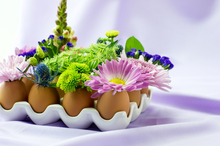 modele de deco de paques avec coquille d oeuf vidée et des brins de fleurs à l intérieur, centre de table Pâques