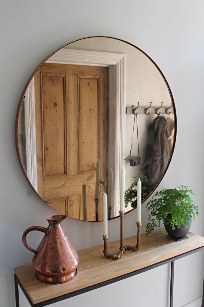 meuble couloir blanc et bois avec finitions noir matte, modèle de miroir rond et objets décoratifs de cuivre et or