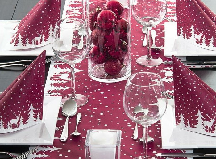 nappe de table couleur bordeau, serviettes pliées, décoration avec des boules de Noel
