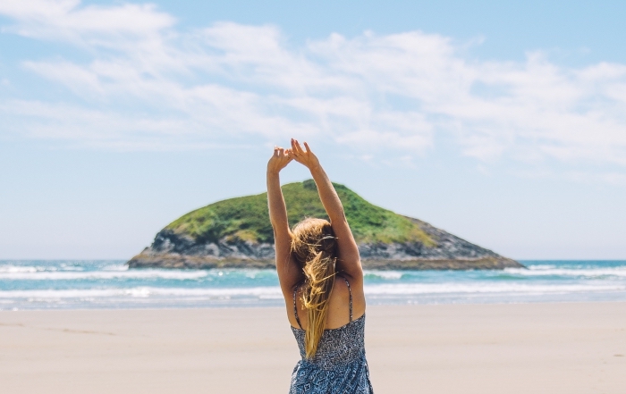 jeune fille aux cheveux ombrés sur la plage habillée en robe bleu foncé et blanc avec brettelle à design géométrique