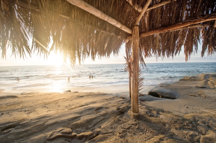 fond d écran magnifiqu au bord de la mer, photo de la plage au sable doré avec une pergola à paille et rayons du soleil