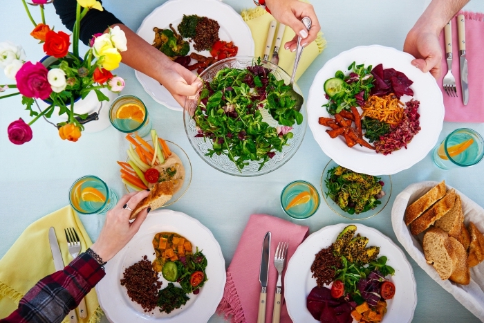 idée repas convivial entre amis, déco de table avec nappe bleu pastel et serviette rose avec franges, salade en épinards et chou rouge 