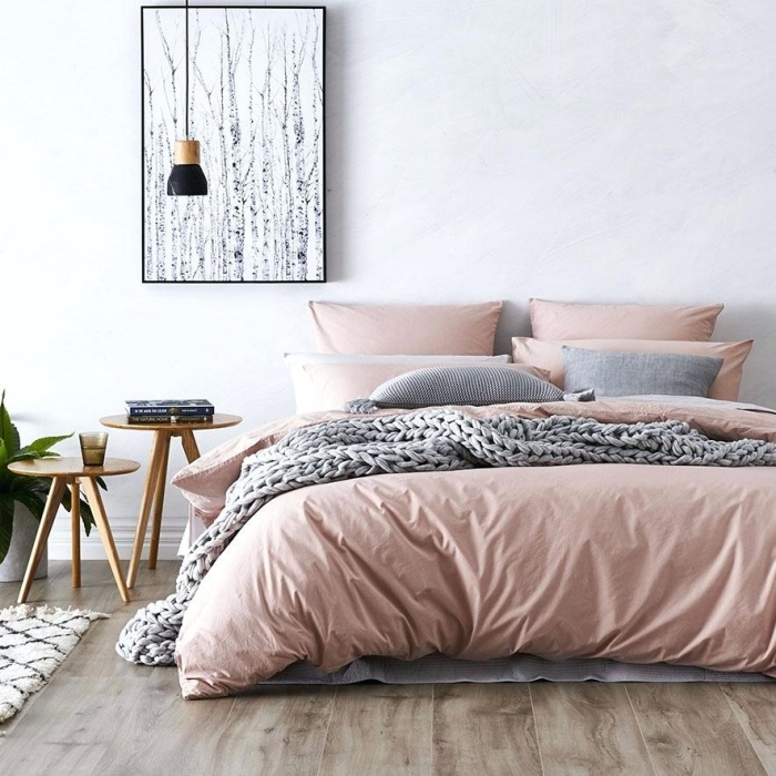 modèle de chambre rose et gris aux murs blancs avec parquet de bois foncé, déco de grand lit au linge rose poudré et coussins gris