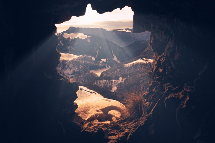 image fond d écran sombre avec un paysage d'oeil d'oiseau, vue d'une grotte vers les montagnes et les champs verts