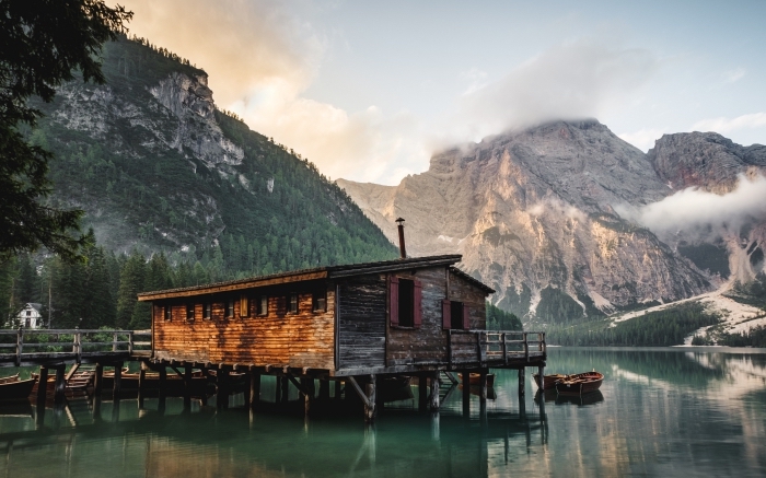 photo d'une maison en bois au bord de lac et dans les montagnes pour un fond d écran paysage au lever du soleil