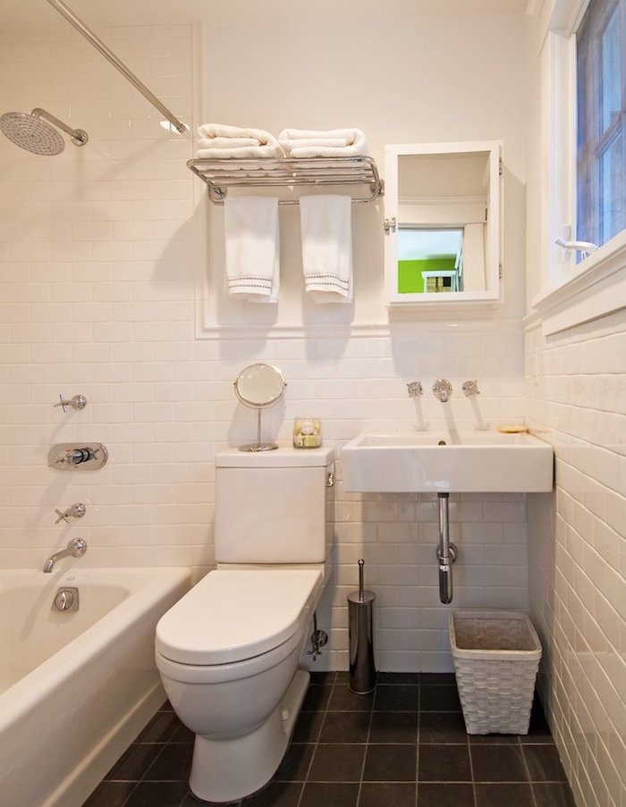 amenagement de petite salle de bain en longueur avec sol carrelage gris anthracite, mur carrelage blanc, baignoire à poser blanche, wc et lavabo blanc