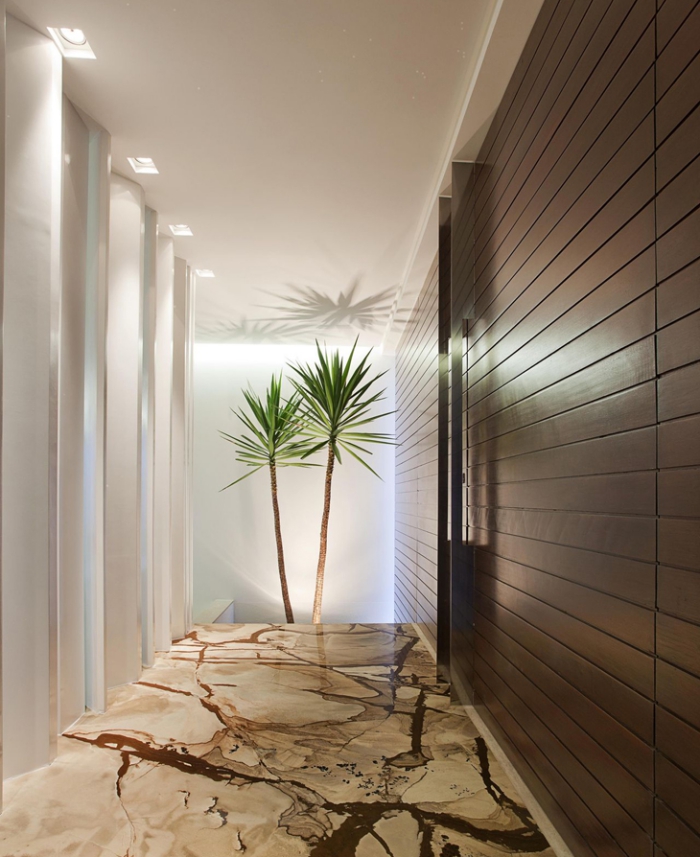 ambiance luxueuse dans un couloir au plafond blanc et plancher beige et marron, plantes vertes dans l'intérieur
