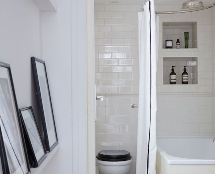 decoration petite salle de bain blanche avec baignoire blanc, niche murale rangement, wc noir et blanc et deco cadres graphiques