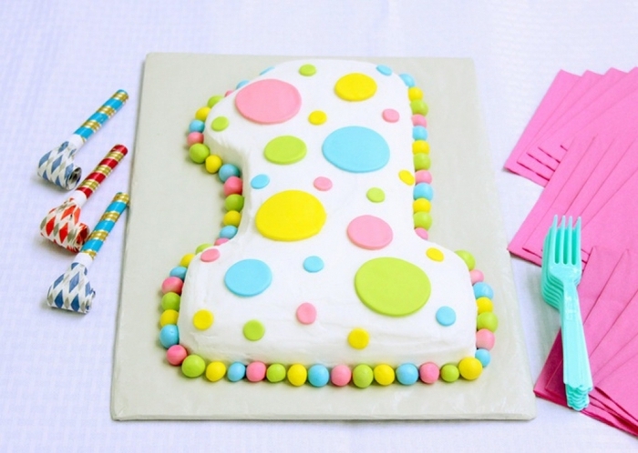 gateau anniversaire 1 an en forme de chiffre recouvert de glaçage blanc et de ronds colorés en pâte à sucre