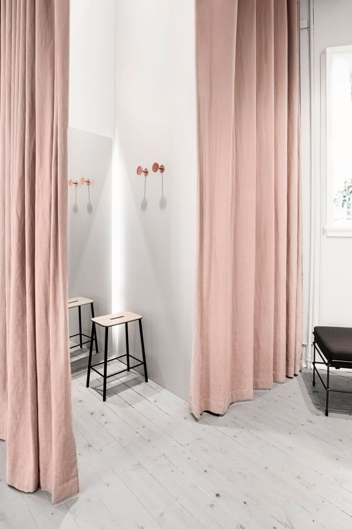 décoration d'intérieur moderne aux murs blancs avec rideaux longs de couleur rose poudré et tabouret en bois et noir mate