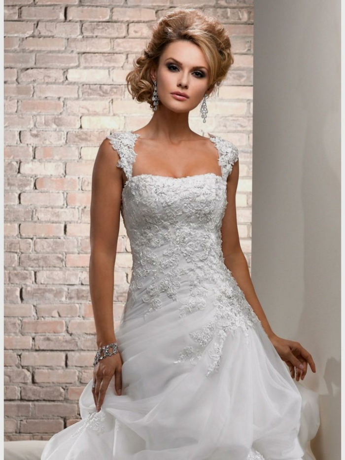jolie robe de mariée, robe boheme mariage, coiffure chignon sophistiqué, mur en briques