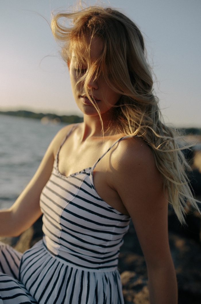jeune femme aux cheveux longs ombrés de couleur blond foncé et blond caramel, modèle de robe marine rayée