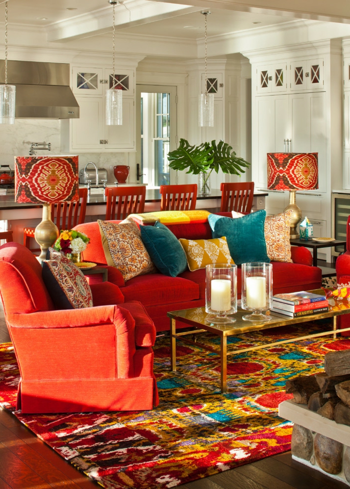 tapis en couleurs radiantes, table en verre et cadre doré, grand sofa rouge