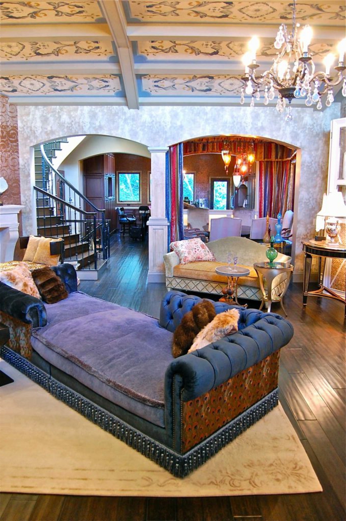 escalier tournant, grand sofa moelleux en bleu, chandelier pampilles, grande maison à plan ouvert