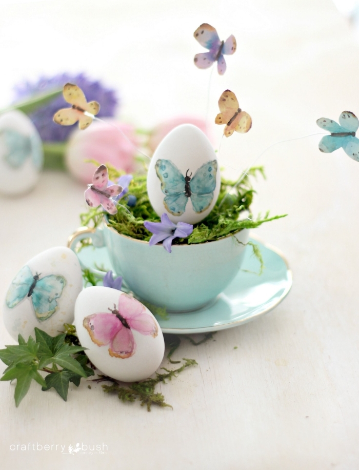 arrangement de table de paques avec service de thé de nuance turquoise et oeuf à coquille blanche décoré de papillons