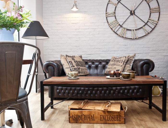 exemple de salon industriel avec mur en papier peint brique blanche et meubles de bois foncé, déco avec coussins marron
