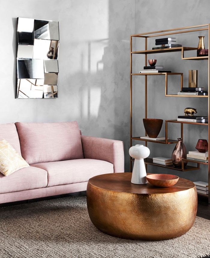 décorer un salon aux murs béton avec étagère à design cuivré de style industriel, modèle de canapé rose poudré