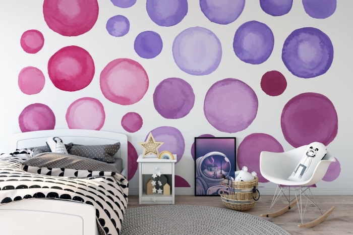 idée déco chambre d'enfant avec tapis rond gris et lit blanc, revêtement mural en papier peint blanc à cercles violet et rose
