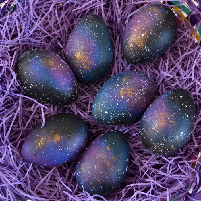 idée pour une décoration de paques originale à effet galaxy avec peinture noire et violet, noeud d'oeufs de paques foncés