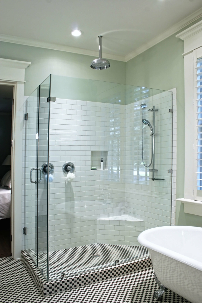 douche italienne en verre transparent en forme rectangulaire, carrelage en noir et blanc aux motifs d'échiquier, baignoire blanche avec des pieds en style ancien