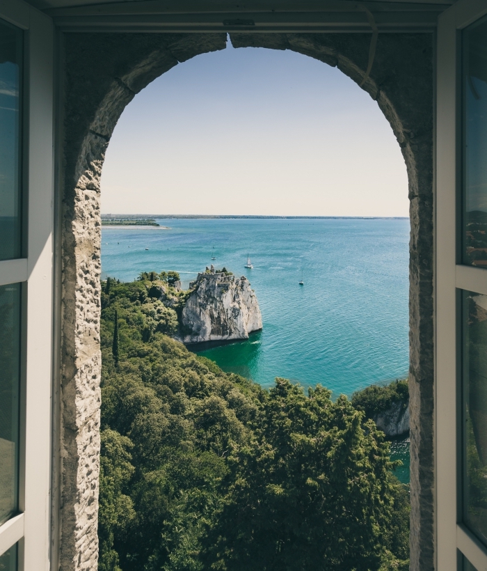 image fond d écran, vue par la fenêtre vers eau turquoise et rochers sur un ile, paysage spectaculaire pour wallpaper ordinateur
