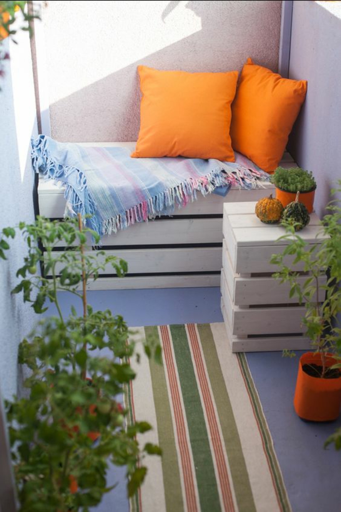 idee deco terrasse, balcon fleuri, palettes transformées en meubles, banc deux places et petite table avec petit pot plante verte, tapis en style ethnique