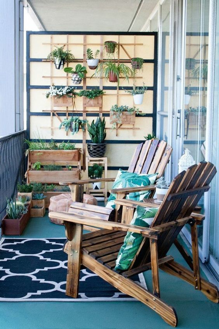 balcon fleuri en style scandinave, deux fauteuils en bois marron foncé, mur avec des pots avec des plantes vertes et des cactus, tapis en blanc et bleu marine