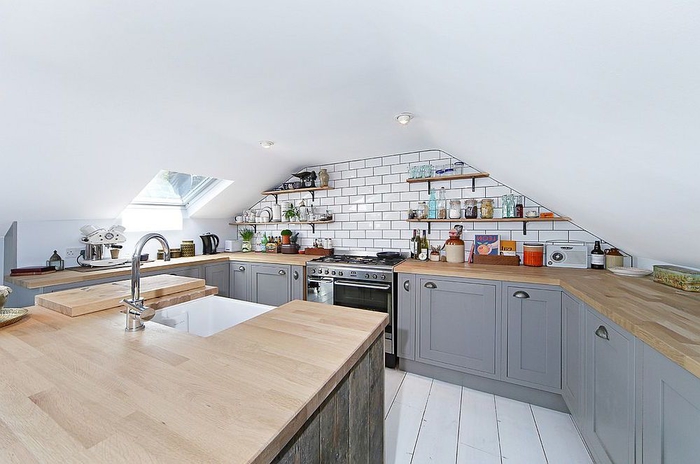 petite cuisine grise et bois aménagée sous combles et agrandie visuellement par le blanc aux murs et au sol