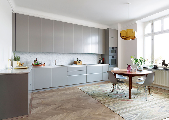 une cuisine grise et blanche élégante de style scandinave aménagée en l, au design minimaliste avec ses meubles sans poignées