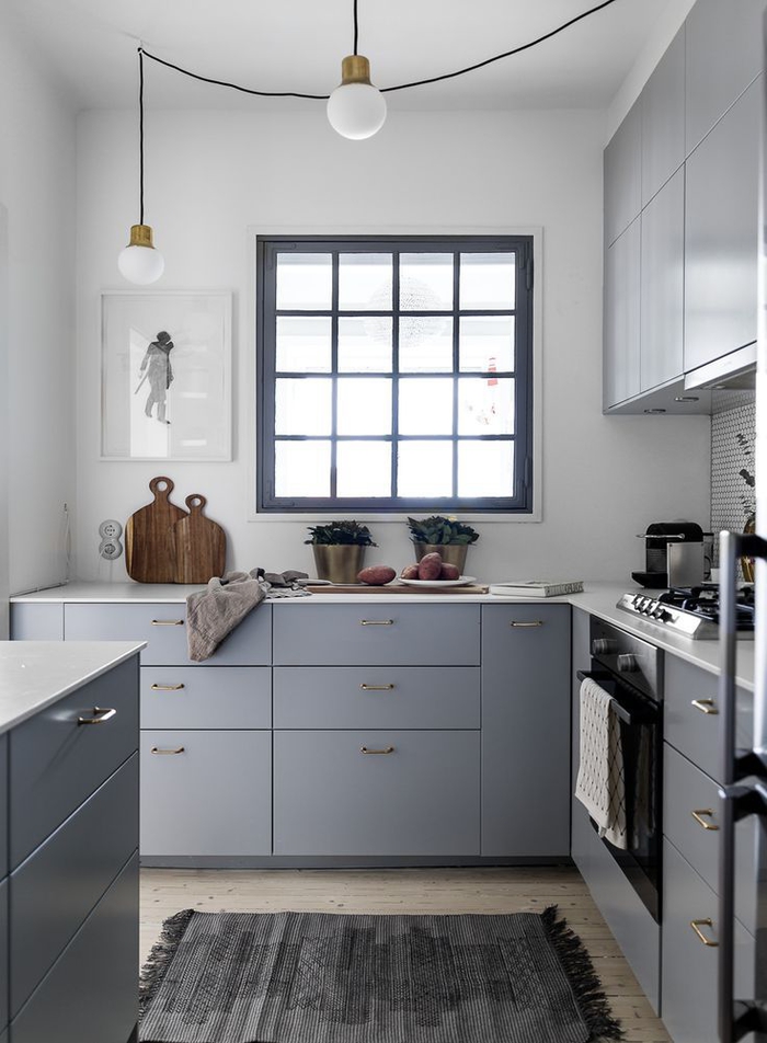 une cuisine gris clair de petite surface, de style scandinave épuré avec des murs blanc et parquet en bois clair
