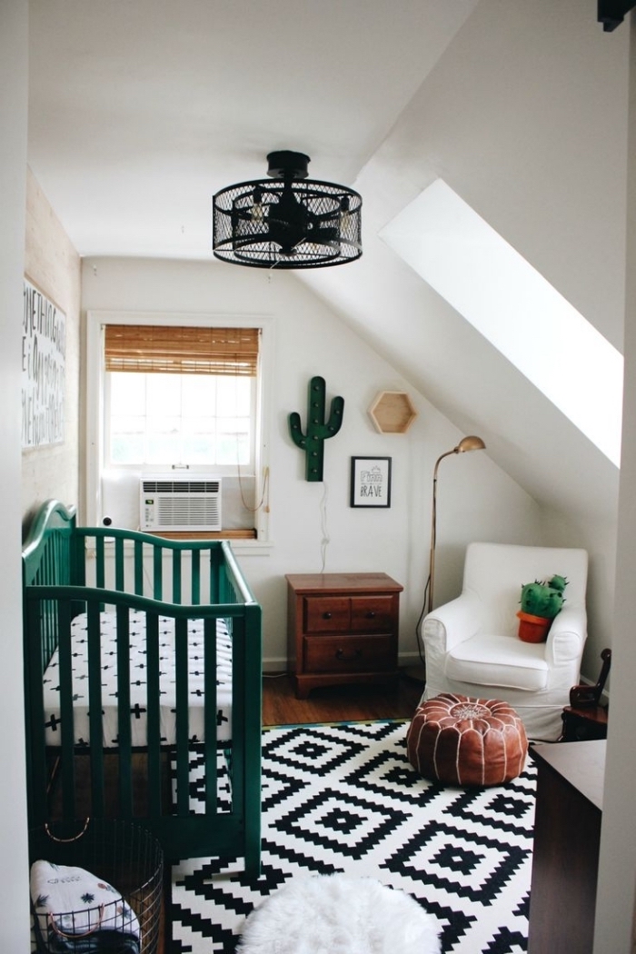 chambre bébé garçon sous pente avec ambiance bohème chic, lampadaire noir et lit nouveau-né en vert foncé, modèle de tapis blanc et noir à design géométrique