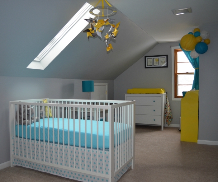 chambre sous pente aux murs blancs avec meubles blancs et accents vibrants jaune et bleu, mobile bébé jaune et gris