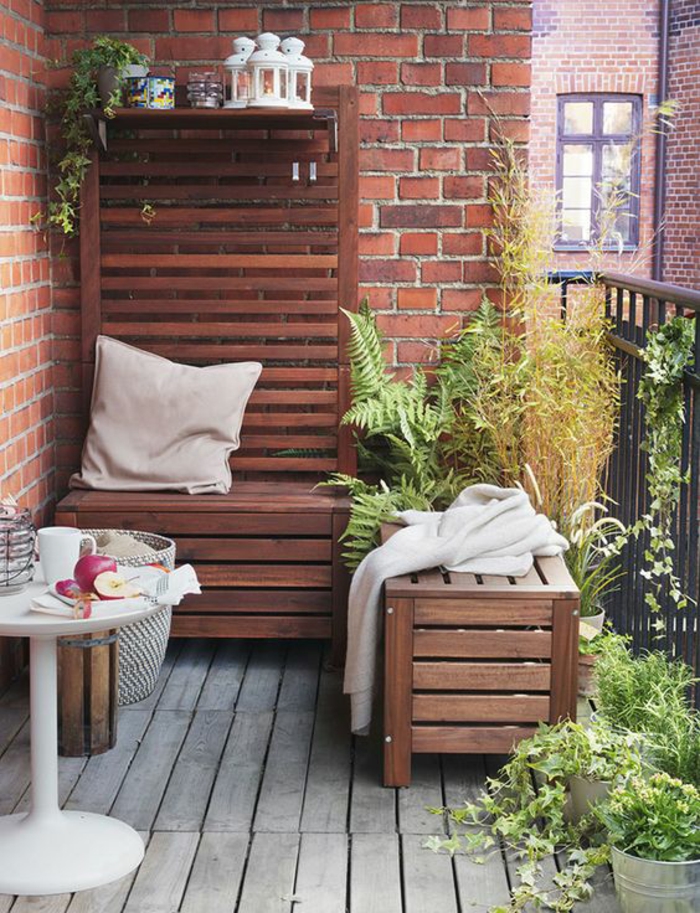 idee deco terrasse, mur en briques rouges, sol en bois de palettes grises, table ronde en plastique blanche, fauteuil deux places et tabouret en palettes