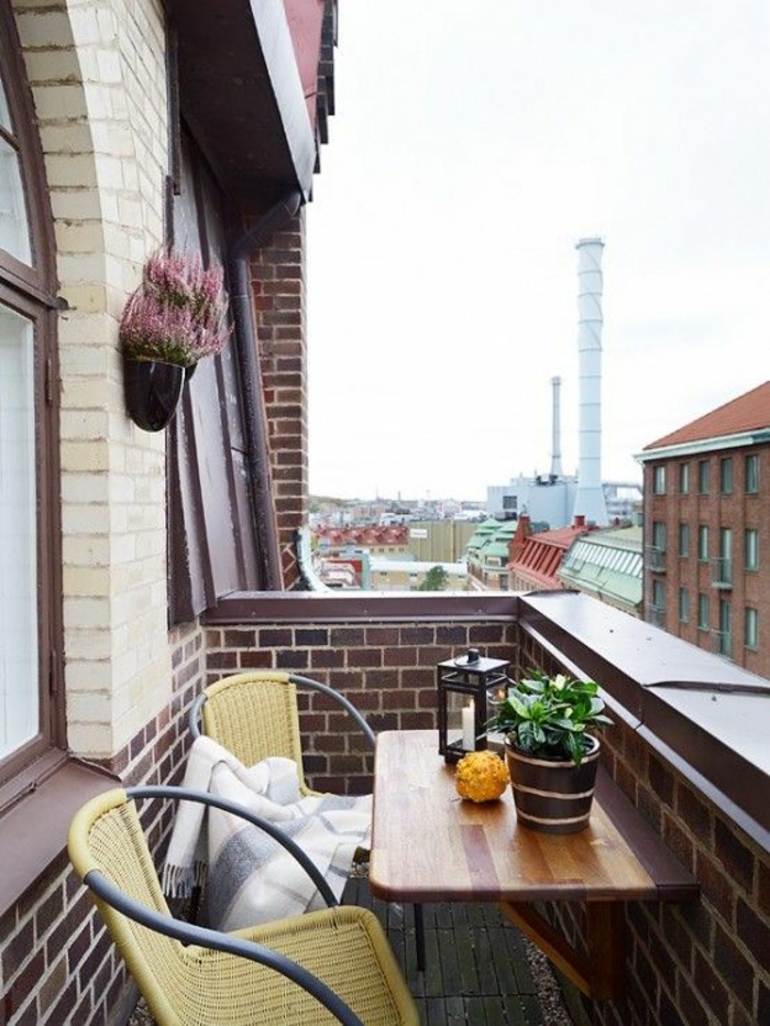 deux chaises en métal noir et en plastique jaune, table pliable, decoration terrasse exterieur, idée déco terrasse, vue sur un établissement en briques rouges, ambiance nordique