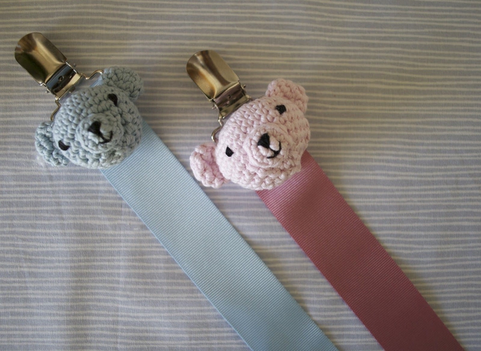 une pince clip attache tetine en métal qui permet de fixer la sucette sur le vêtements de bébé, modèle d'attache sucette décoré avec une tête d'ourson au crochet