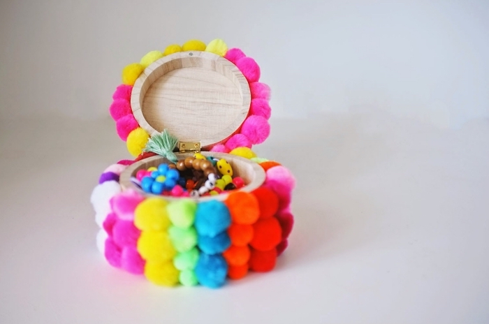 objet décoratif en forme de mini boîte à bijoux de bois clair couverte de petits pompons en couleurs variées